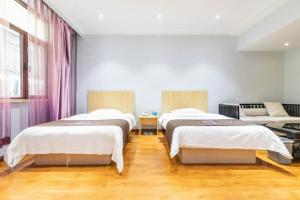 three beds in a room with wooden floors at Pai Hotel Tianjin Binguan Metro Station Municipal Government in Tianjin