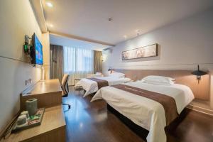 a hotel room with two beds and a television at Jinjiang Inn Select Xuzhou Suning Plaza Jinguang East Road in Xuzhou
