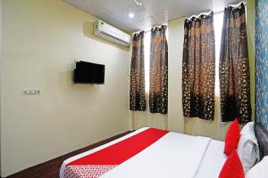 a bedroom with a bed with curtains and a tv at Hotel O Platinum Inn in Faridabad