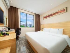 a hotel room with a large white bed and a desk at City Comfort Inn Nanning Wuyi Fude in Nanning +40 photos