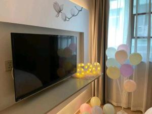 a flat screen tv sitting next to a window with balloons at Magnotel Hotel Wuhan Jiangtan Lihuangpo Road Pedestrian Street in Wuhan