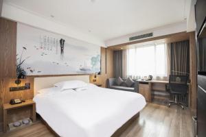 a bedroom with a large white bed and a desk at Starway Hotel(Shuiximen Street,Nanjing) in Nanjing