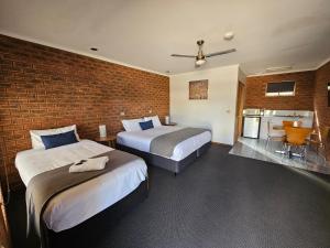 a bedroom with two beds and a brick wall at Bridge Motor Inn Tocumwal in Tocumwal