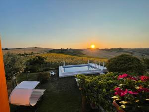 a pool in a garden with the sunset in the background at AGRITURISMO LA MOROLLA in Marsciano