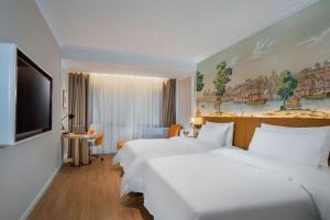 a hotel room with two beds and a flat screen tv at Vienna Hotel Tianjin Chentangzhuang Metro Station in Tianjin +72 photos