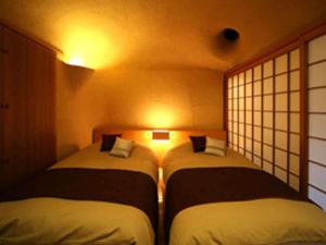 two beds in a small room with lights at kanazawayuwakuonsen nihonryourisakaeya in Kanazawa