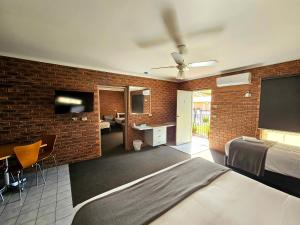 a bedroom with a bed and a brick wall at Bridge Motor Inn Tocumwal in Tocumwal