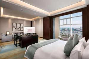 a bedroom with a large bed and a television in it at Ramada by Wyndham Wuhan Dongxihu in Wuhan