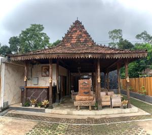 a small house with a roof with a bench at Ijen Cottages in Jambu