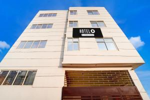 a tall white building with a sign on it at Hotel O Deva road Formerly Hotel Sunrise Inn in Lucknow