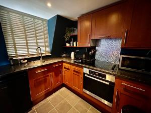 a kitchen with wooden cabinets and a sink at Stylish City Centre Apartment in Bath