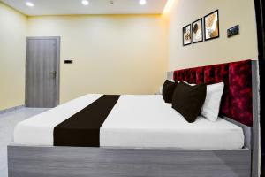 a bedroom with a large white bed with a red headboard at Super Townhouse Taramandal Near Sahara States in Bhauvāpār