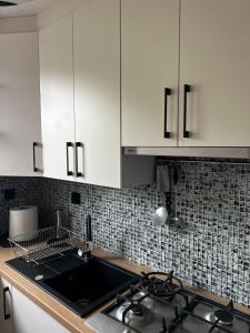 a kitchen with white cabinets and a stove top oven at ZieloneMistrzejowice in Kraków