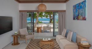 a living room with a couch and a view of the ocean at Avani+ Barbarons Seychelles in Grand'Anse