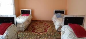 a room with three beds and a rug at Porasht homestay in Farish