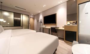 a hotel room with a white bed and a kitchen at Busan Myeongji Ciel Ocean Hotel in Busan