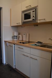 eine Küche mit Mikrowelle und Spüle in der Unterkunft Appartements Bürger in Krumpendorf am Wörthersee