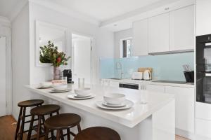 シドニーにあるRushcutters Bay Retreat with Balcony - New Listingのキッチン(白いカウンター、スツール付)