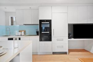 シドニーにあるRushcutters Bay Retreat with Balcony - New Listingのキッチン(白いキャビネット、黒いオーブン付)