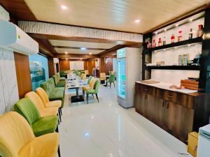 a restaurant with a long table and green chairs at Hotel Laxmi villa in Naini