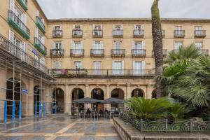 a large building with tables and chairs in a courtyard at Plaza Nueva in Bilbao