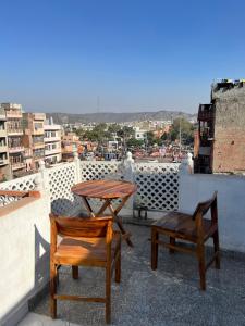 zwei Holzstühle und ein Tisch auf dem Dach in der Unterkunft Arch Heritage in Jaipur