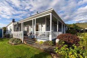 里夫顿Haere Mai Reefton Heritage Holiday Home的一座有门廊和院子的白色房子 更多18张照片
