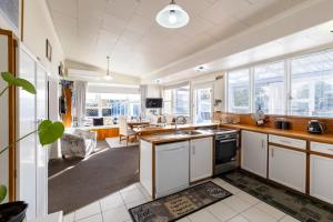 里夫顿Haere Mai Reefton Heritage Holiday Home的带白色橱柜的厨房和客厅