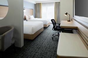 a hotel room with two beds and a desk at Fairfield Inn & Suites by Marriott Montreal Airport in Dorval