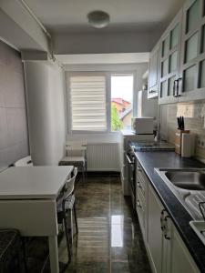 オトペニにあるApartament in Otopeniの白いキャビネット、シンク、窓付きのキッチン +14枚の写真
