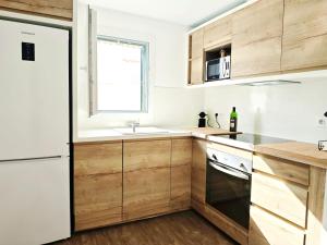 a kitchen with wooden cabinets and a white refrigerator at Es Canto in Cala Blanca