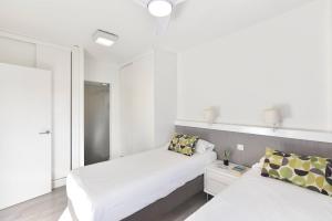 a white bedroom with two beds and a mirror at Modern Iguazu Apartment in Playa del Ingles +16 photos
