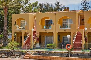 duży żółty budynek z palmami przed nim w obiekcie Apartament Tisalaya 44 By Pride Holiday Rentals w mieście Maspalomas