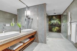 un bagno con due lavandini e una doccia di Kempinski Seychelles Resort a Baie Lazare Mahé