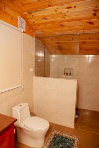 La salle de bains est pourvue de toilettes blanches et de plafonds en bois. dans l'établissement Gangtey Tent Resort, à Gangtey Gonpa