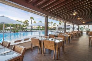 a restaurant with tables and chairs and a pool at Wyndham Grand Algarve Quinta do Lago in Quinta do Lago