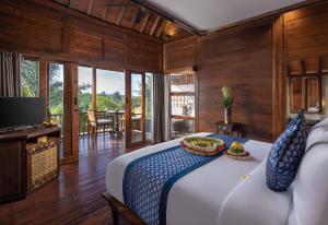 a bedroom with a large bed and a television at Sacred Valley by GenuineHost in Tegalalang