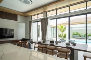 ein Wohnzimmer mit einem großen Tisch und Stühlen in der Unterkunft Mouana Breeze Mai Khao 4-bedroom Pool Villa 9920 in Mai Khao Beach