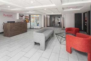 a lobby with a couch and two red chairs at Ramada by Wyndham Milwaukee in Milwaukee