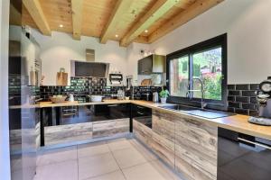 - une cuisine avec des murs noirs et blancs et des plafonds en bois dans l'établissement Résidence La Moutelette - Chalet La Moutelette - 14 Personnes - Montriond MAE-3831, à Montriond