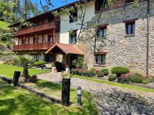 una casa de piedra con un jardín delante en Hotel-Apartamento Rural Atxurra, en Bermeo