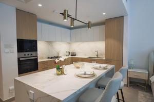 a kitchen with a large island with chairs in it at Stylish Studio at Berkeley Place by Ellington in Dubai