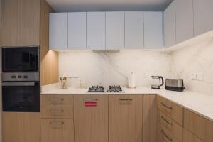 a kitchen with white cabinets and a stove top oven at Stylish Studio at Berkeley Place by Ellington in Dubai