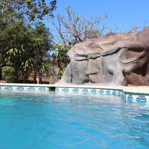 a swimming pool next to a large rock at Cabinas Liz in Veintisiete de Abril