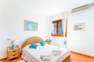 a white bedroom with a bed with blue pillows at Villa Giulia in Is Morus