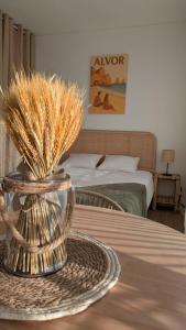 a room with a bed and a table with a vase with grass at Penthouse Studio Sea View in Alvor