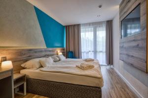 a bedroom with a large bed with a blue wall at Hotel Szieszta in Sopron