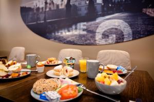 a wooden table topped with plates of food and orange juice at Motel One Prague-Florentinum in Prague