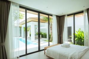 Schlafzimmer mit einem Bett und großen Glasfenstern in der Unterkunft Mouana Breeze Mai Khao 4-bedroom Pool Villa 9920 in Mai Khao Beach + 59 Fotos