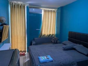 a blue bedroom with a bed and a couch at Vins Room at Vivo Apartemen in Yogyakarta